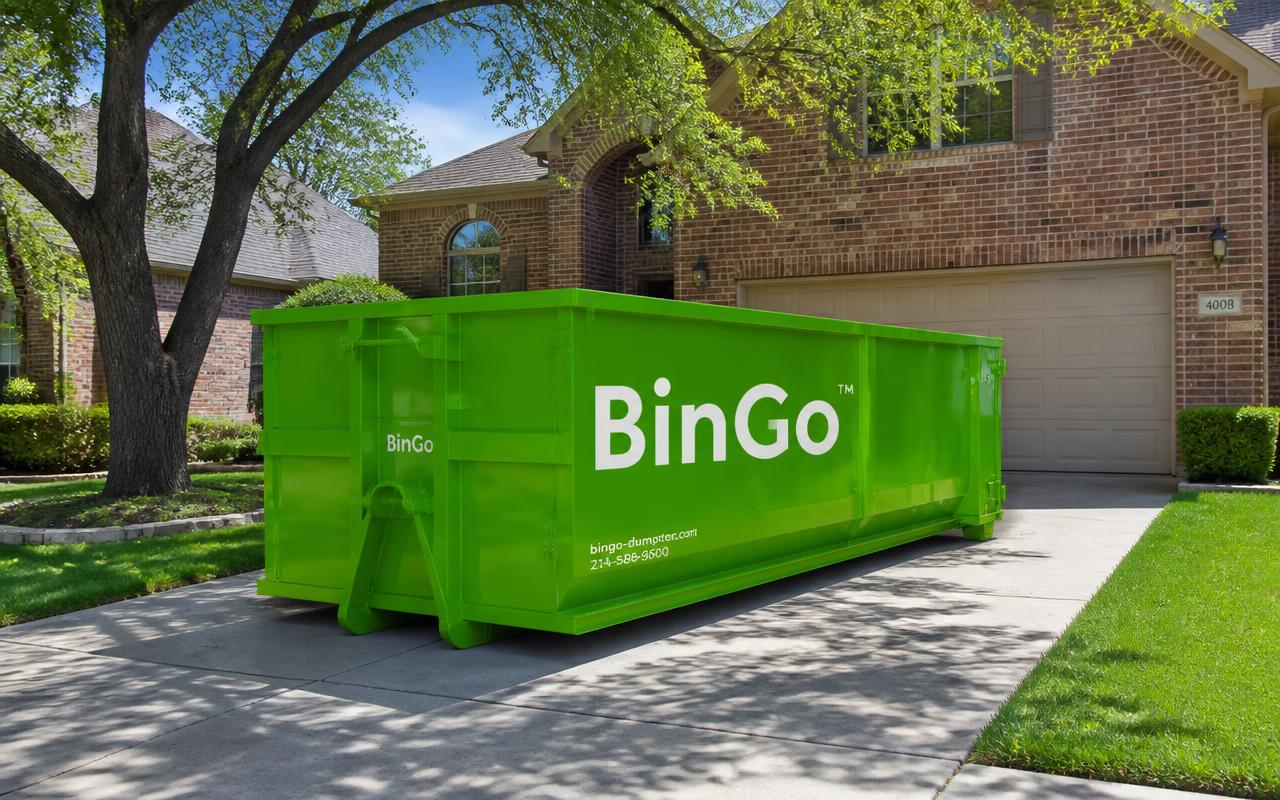 Green BinGo roll-off dumpster on a shaded suburban driveway in Coppell, TX