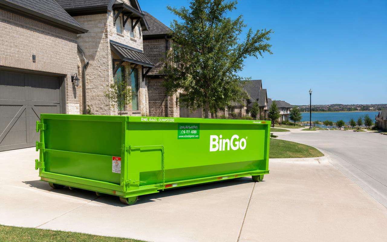 Green BinGo roll-off dumpster on a newer suburban driveway in Little Elm, TX with the lake in the background