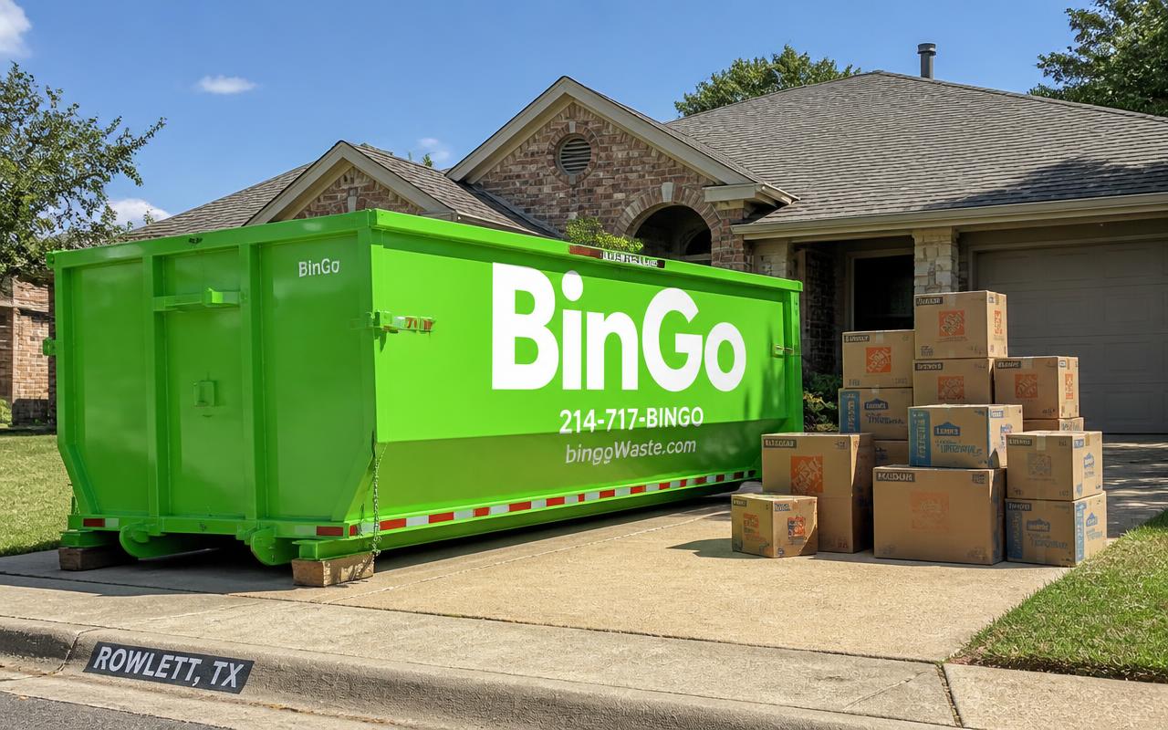 Green BinGo roll-off dumpster on a driveway in Rowlett, TX with stacked cleanout boxes beside it